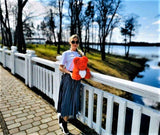 A woman holding a rose bear while walking near a lake